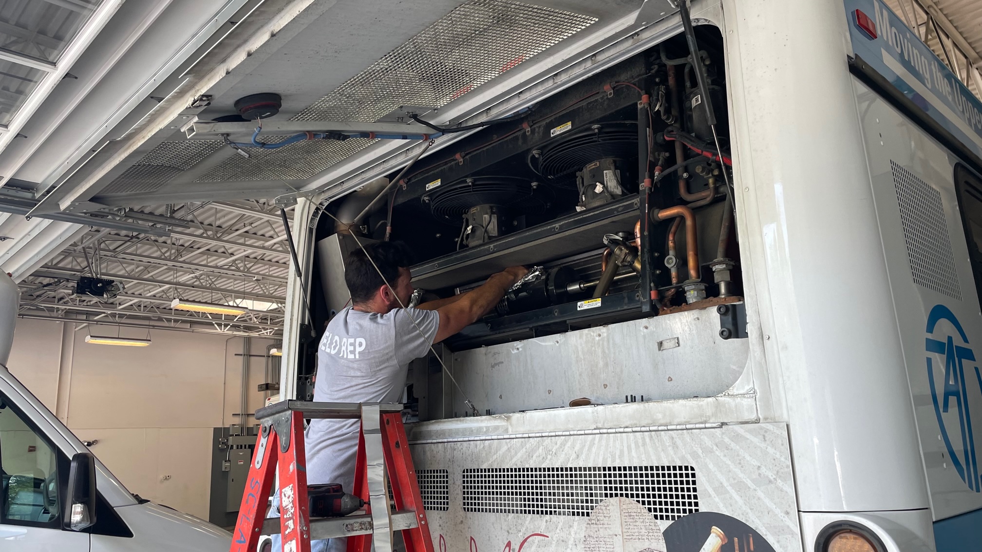 Field rep installing air purification system in AT bus